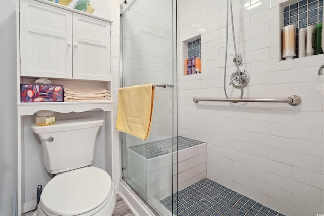 bathroom with toilet and a shower with shower door