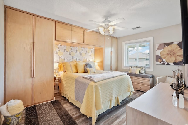 bedroom with ceiling fan, dark hardwood / wood-style flooring, and a textured ceiling