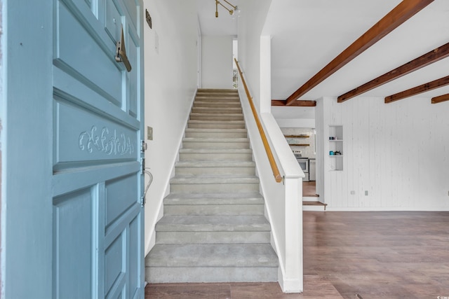 stairs featuring beamed ceiling, hardwood / wood-style floors, and wooden walls