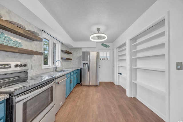 kitchen with light hardwood / wood-style flooring, stainless steel appliances, blue cabinets, and sink