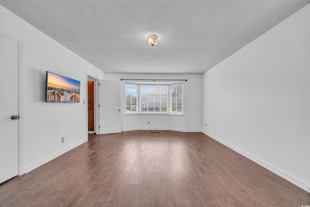 unfurnished room featuring a textured ceiling and dark hardwood / wood-style floors