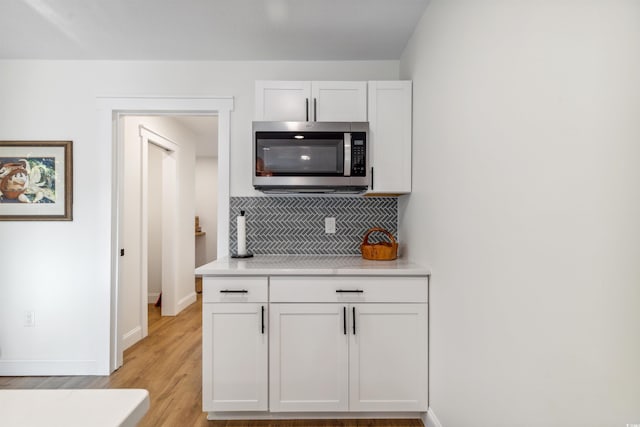 kitchen featuring tasteful backsplash, white cabinetry, and light hardwood / wood-style flooring