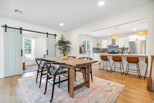 dining space featuring a barn door, light wood-type flooring, and sink