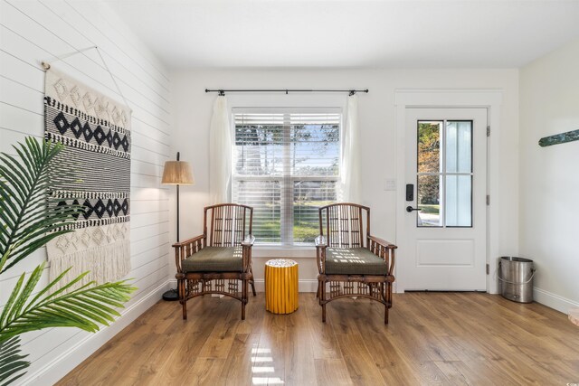 living area featuring wooden walls, plenty of natural light, and light wood-type flooring