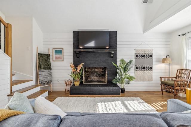 living room with wood walls, a fireplace, and wood-type flooring