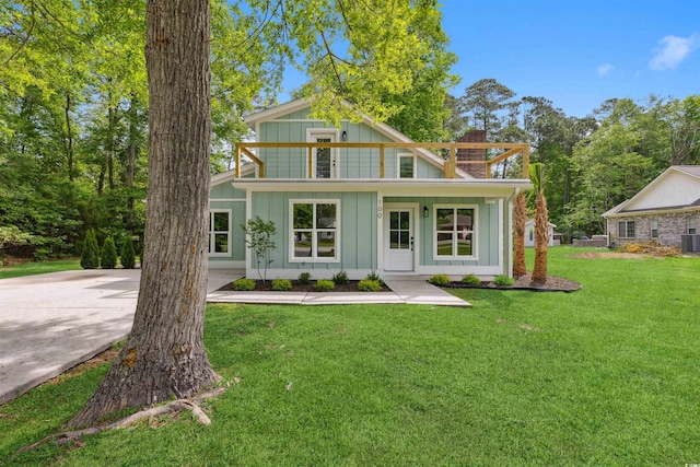 view of front of house featuring central air condition unit, a balcony, and a front lawn