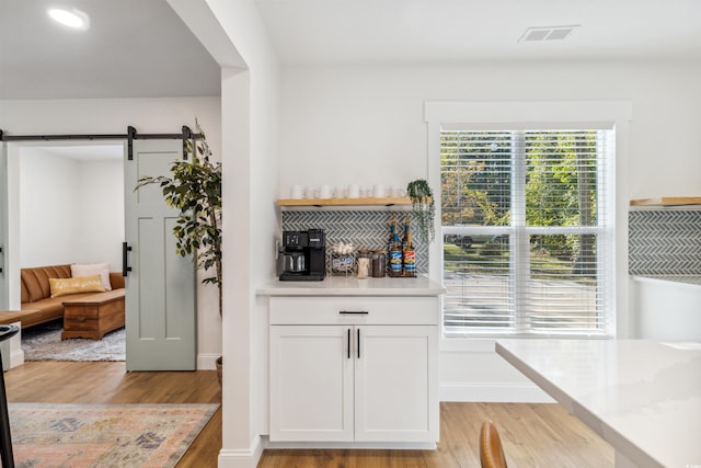 kitchen featuring white cabinets, a barn door, and light wood-type flooring