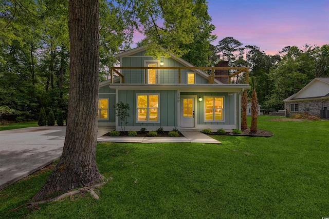 view of front of house with a lawn, central air condition unit, and a balcony