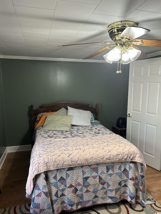 bedroom with hardwood / wood-style floors, ceiling fan, and ornamental molding