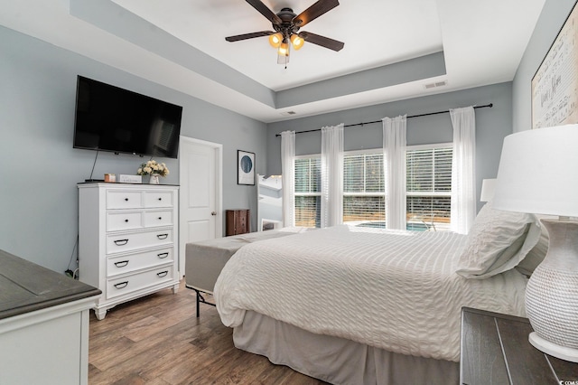 bedroom featuring a raised ceiling, ceiling fan, and dark hardwood / wood-style flooring