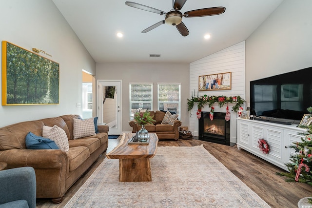 living room with hardwood / wood-style flooring, ceiling fan, and high vaulted ceiling