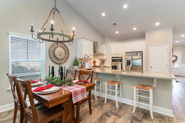 dining area featuring dark wood-type flooring, a notable chandelier, lofted ceiling, and sink