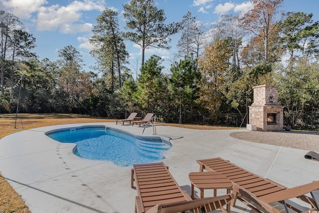 view of swimming pool with an outdoor stone fireplace and a patio area