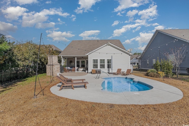 rear view of property featuring a fenced in pool, a patio area, a fireplace, and a yard