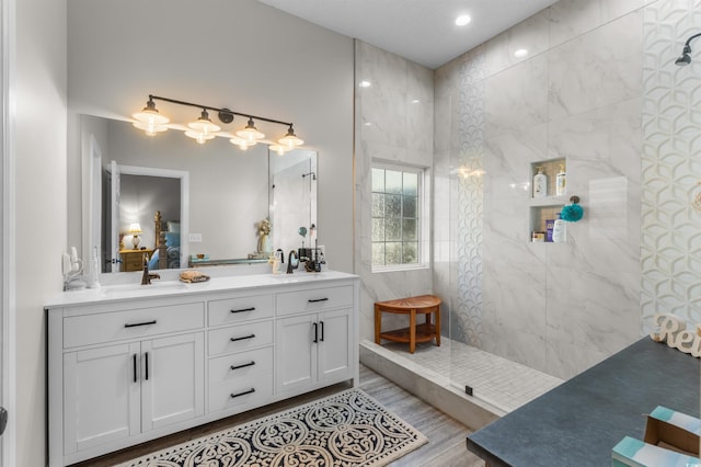 bathroom featuring a tile shower, vanity, and wood-type flooring