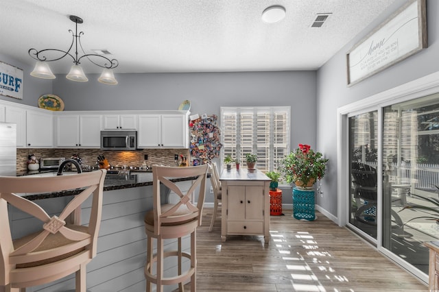 kitchen featuring white cabinets, decorative backsplash, hardwood / wood-style flooring, and plenty of natural light