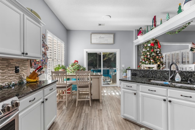 kitchen featuring light hardwood / wood-style floors, white cabinetry, and dark stone countertops