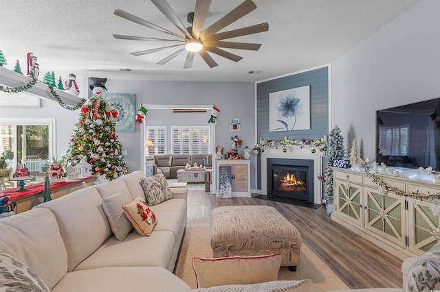 living room with hardwood / wood-style floors, a textured ceiling, and ceiling fan