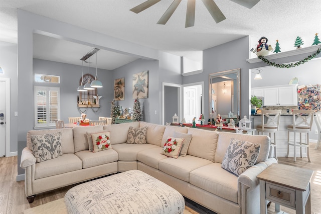 living room with ceiling fan, light hardwood / wood-style floors, and a textured ceiling