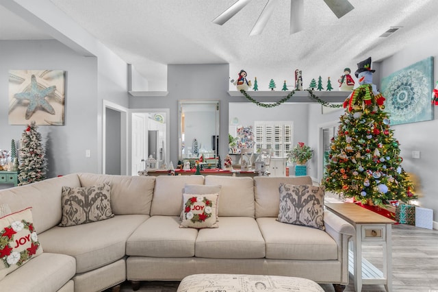 living room with hardwood / wood-style floors, a textured ceiling, and ceiling fan