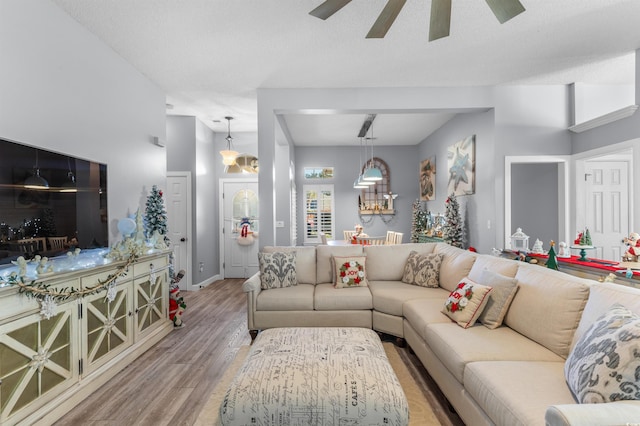 living room with ceiling fan, light wood-type flooring, and a textured ceiling