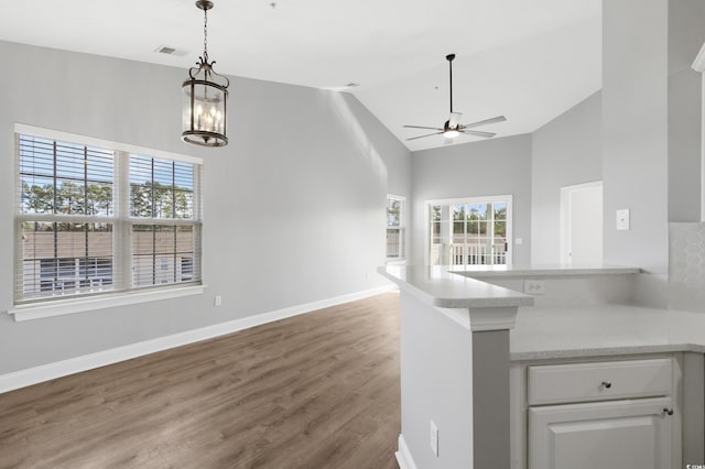 kitchen featuring white cabinetry, hanging light fixtures, dark wood-type flooring, high vaulted ceiling, and ceiling fan with notable chandelier