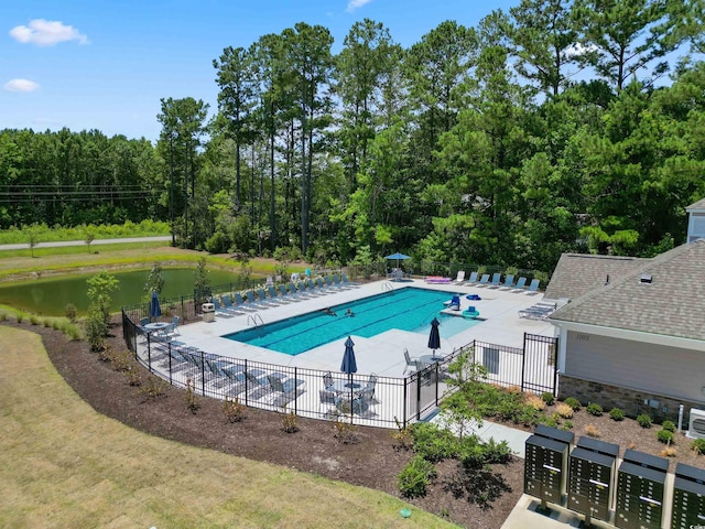 pool featuring a water view, a patio, and fence