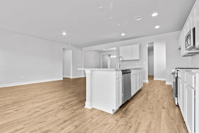 kitchen featuring light stone countertops, stainless steel appliances, light hardwood / wood-style floors, a center island with sink, and white cabinets