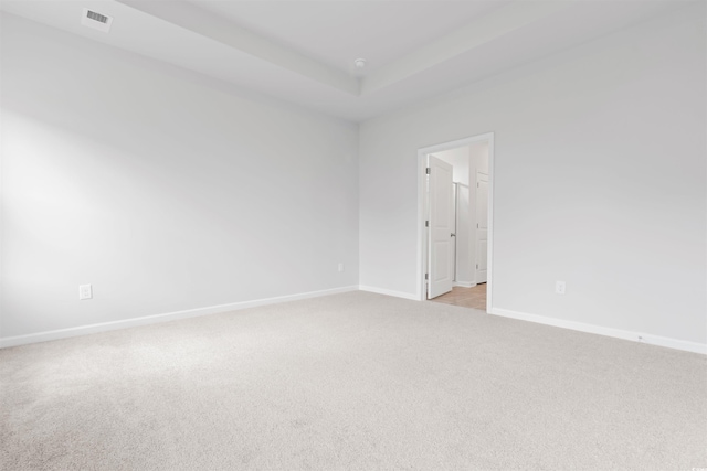 carpeted spare room with a tray ceiling