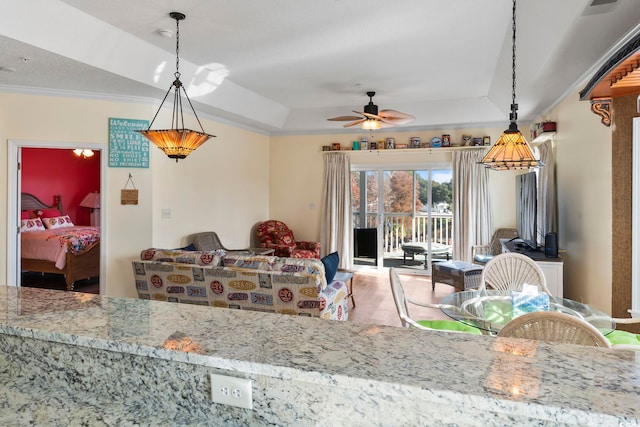 kitchen with ceiling fan, light stone counters, pendant lighting, wood-type flooring, and a tray ceiling