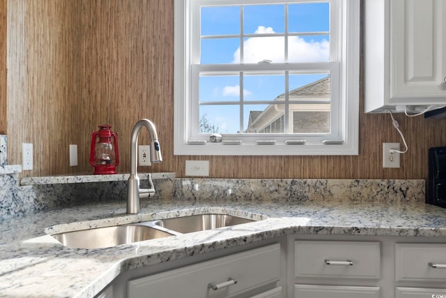 kitchen with white cabinets, light stone countertops, and sink