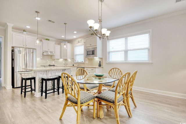 dining area with a chandelier, ornamental molding, and light hardwood / wood-style flooring