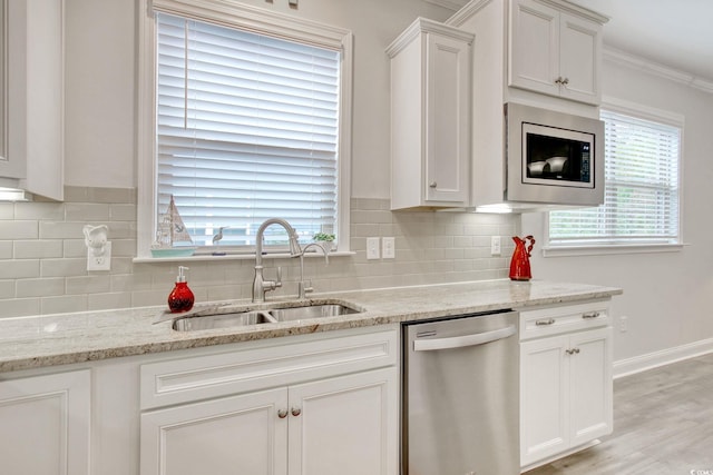 kitchen with sink, ornamental molding, stainless steel appliances, and a wealth of natural light