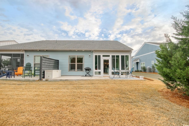 rear view of property with a yard, a patio, and a sunroom