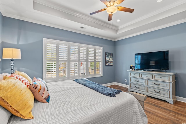 bedroom with wood-type flooring, a tray ceiling, ceiling fan, and crown molding