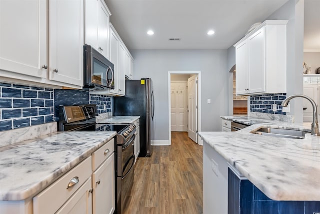 kitchen featuring wood-type flooring, white cabinetry, stainless steel electric range oven, and sink