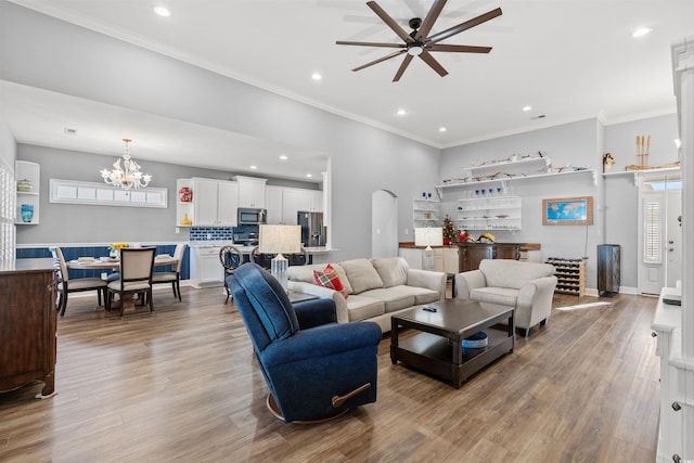 living room featuring ceiling fan with notable chandelier, light hardwood / wood-style flooring, and crown molding