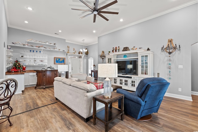 living room with ceiling fan with notable chandelier, hardwood / wood-style flooring, and ornamental molding