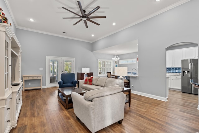 living room featuring ceiling fan with notable chandelier, dark hardwood / wood-style floors, ornamental molding, and sink