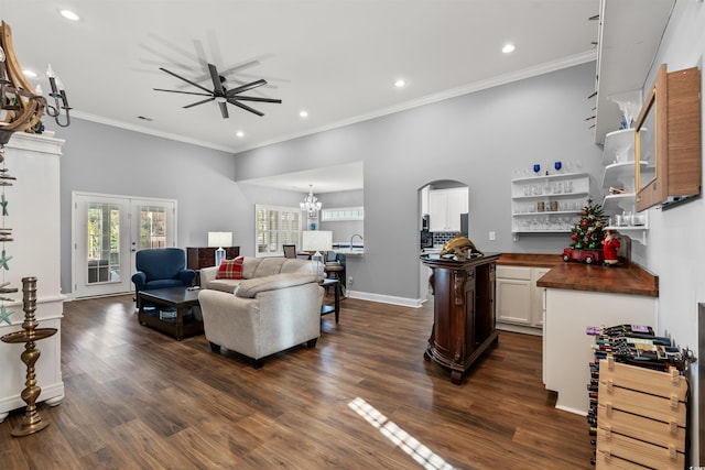 living room with dark hardwood / wood-style flooring, ceiling fan with notable chandelier, and ornamental molding