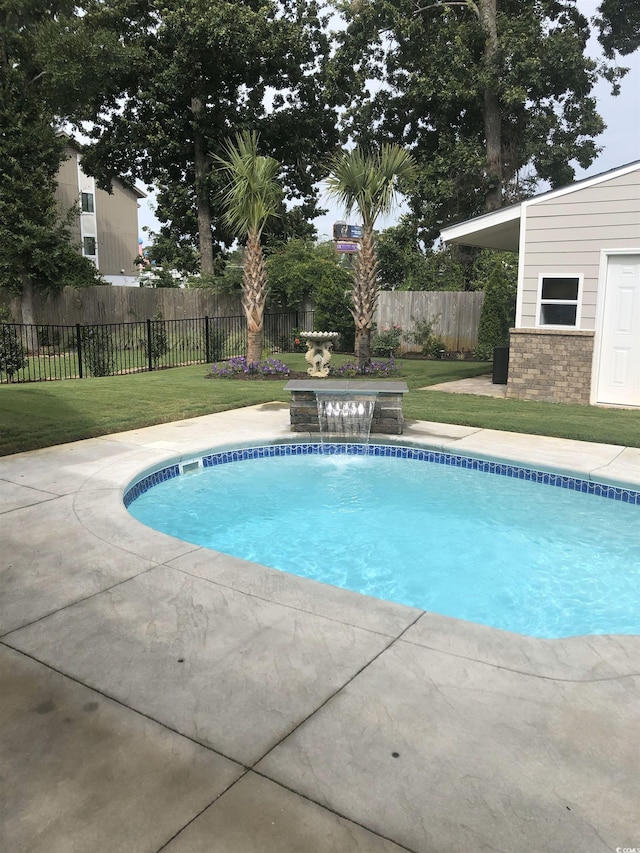 view of swimming pool with pool water feature and a yard