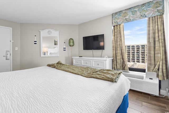 bedroom with hardwood / wood-style floors and a wall unit AC