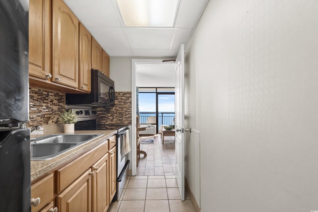 kitchen featuring stainless steel electric range oven, sink, a drop ceiling, tasteful backsplash, and light tile patterned floors