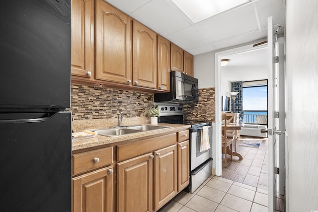 kitchen featuring tasteful backsplash, sink, black appliances, light tile patterned floors, and a water view