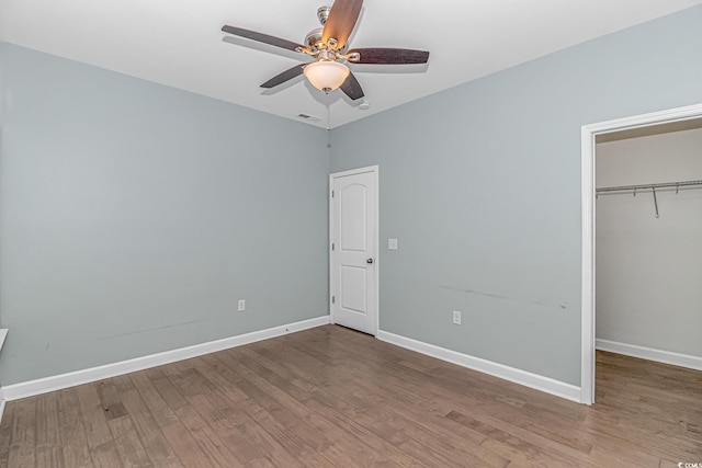 unfurnished bedroom featuring hardwood / wood-style floors, a closet, and ceiling fan