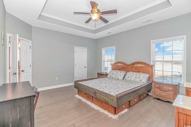 bedroom with multiple windows, a raised ceiling, and ceiling fan