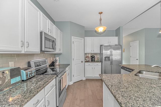 kitchen with hanging light fixtures, sink, appliances with stainless steel finishes, and tasteful backsplash