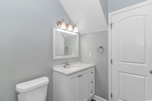 bathroom featuring vanity, toilet, and lofted ceiling