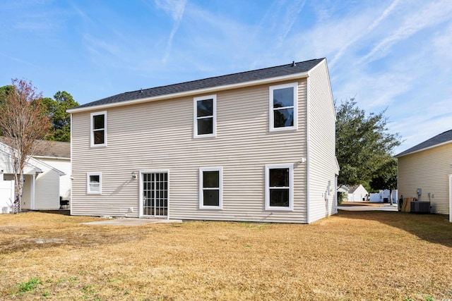 rear view of house featuring central AC and a lawn