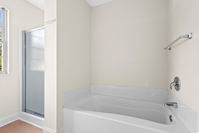 bathroom with plus walk in shower, a healthy amount of sunlight, and hardwood / wood-style flooring